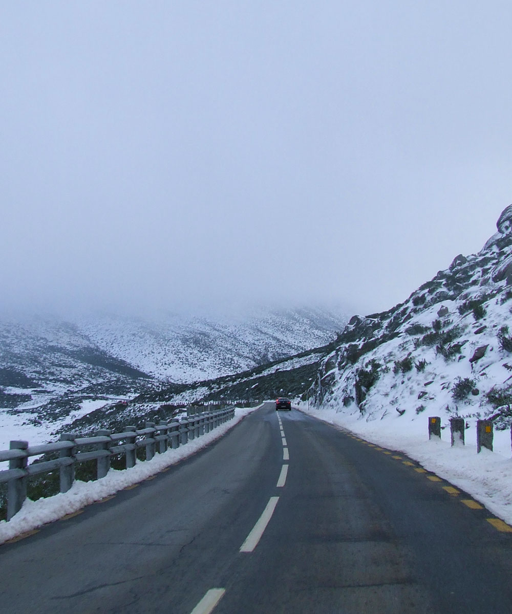 Strada innevata di montagna con un'automobile in transito