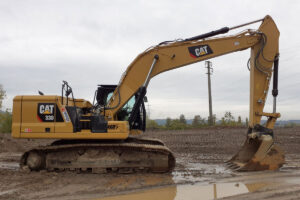 Escavatore cingolato Caterpillar in un cantiere dopo la pioggia con delle pozzanghere