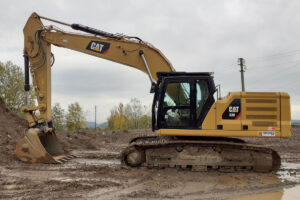 Escavatore cingolato Caterpillar 330 in un cantiere dopo la pioggia con delle pozzanghere