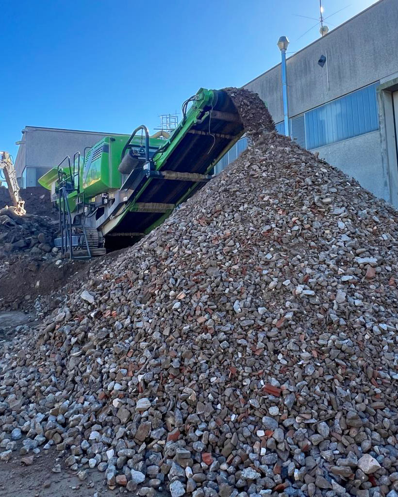 Frantumatore di rifiuti all'opera, la foto mostra una piramide di rifiuti frantumati prodotti dal mezzo